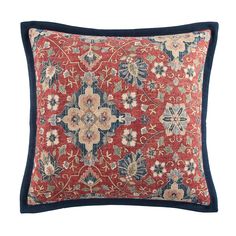 a red and blue pillow with floral designs on the front, along with a navy border