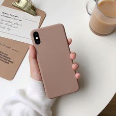 a person holding an iphone in their hand next to a cup of coffee on a table