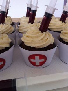 cupcakes with white frosting and red crosses on them are arranged in cups