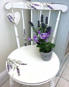 a white chair with purple flowers on it and two hearts painted on the back seat