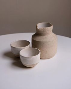 three bowls and a vase sitting on a table