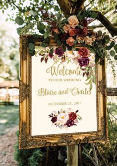 a welcome sign with flowers and greenery on it