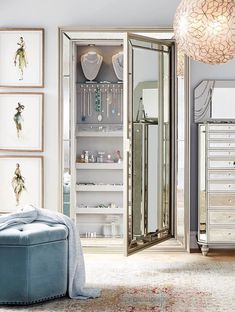 an open mirrored cabinet in a room with pictures on the wall and a blue ottoman