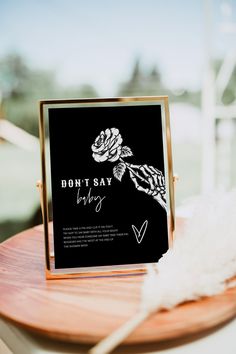 a sign that says don't say baby on it next to a white feather