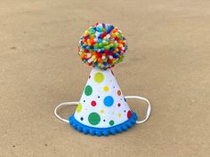 "A MINI party hat made out of colorful polkadot fabric and trimmed with mini bright ocean blue pom poms on bottom and a speckled yarn pom pom on the top.  Attached to a 1/8\" elastic- to be worn comfortably like a headband.  Diameter of hat is 3\", and height 4\". OPTIONS: -Bottom Pom Pom trim color  -Number- with or without  * please provide desired number/outline color in comments section  DOGS:  If you are purchasing for a dog, please provide entire head circumference measurement- start at to Number Outline, Blue Pom Poms, Fall 1st Birthdays, Dog Party Hat, Dog First Birthday, Dog Birthday Hat, Speckled Yarn, Birthday Wreath, Happy Birthday Decor