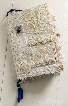 an old book with lace and tassels on it sitting on a white wooden surface