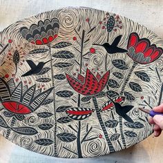 a person is drawing on a plate that has birds and flowers painted on the surface