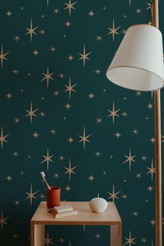 a table with a lamp on it next to a wallpapered background that has gold stars