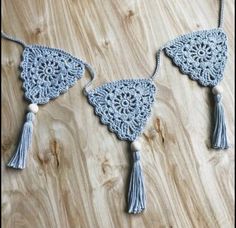 three crocheted tassels hanging on a wooden surface