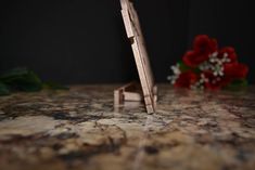 a wooden object sitting on top of a counter next to red flowers and greenery