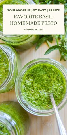 three jars filled with pesto sauce on top of a wooden table next to herbs