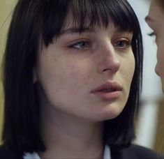 a close up of a person wearing a suit and tie with short hair looking at another persons face