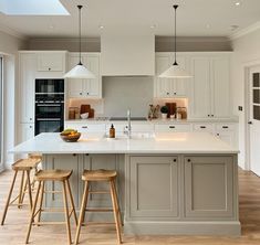 a kitchen with two stools in front of the island and an open floor plan