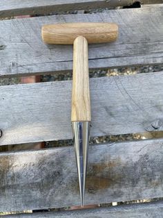 a wooden handle with a metal tip sticking out of it's side on a bench