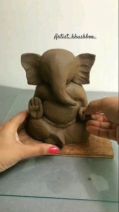 someone is making an elephant out of clay on a piece of wood with their hands