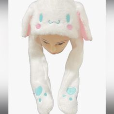 a white bunny hat with pink ears and blue spots on it's face, sitting in front of a white background