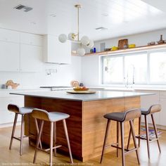 an island in the middle of a kitchen with three stools