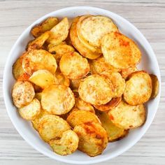 a white bowl filled with fried potatoes on top of a wooden table