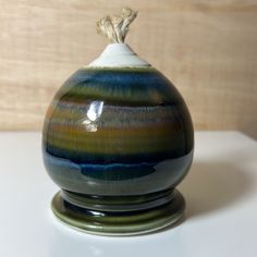 a ceramic container with a rope sticking out of it's top sitting on a table