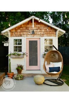 a porch with a swing chair, potted plants and a pink door on it