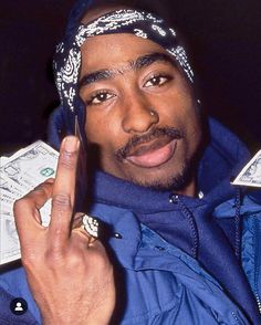 a man in a bandana holding up a cell phone to his ear and pointing at the camera