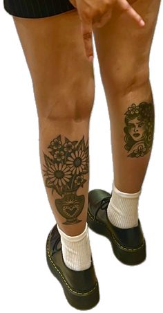 a woman's legs with tattoos on them and her hand pointing at the camera