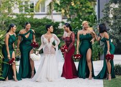 a group of women standing next to each other in long green dresses and holding bouquets