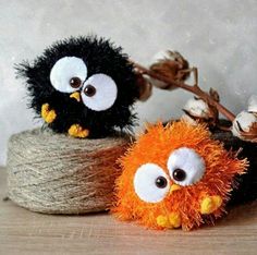 two small stuffed birds sitting on top of a spool of twine next to cotton