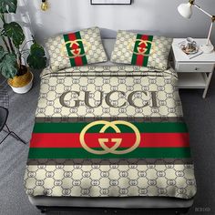 a bed with gucci logo on it in a room next to a table and potted plant