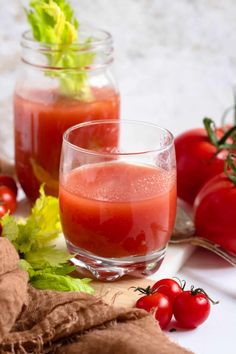 two glasses filled with red liquid next to tomatoes