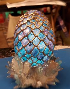 an egg that is sitting on some kind of stand up with blue and gold decorations