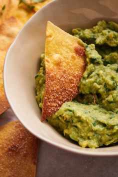 a white bowl filled with guacamole and tortilla chips on the side