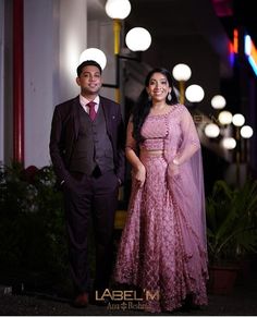 a man and woman standing next to each other in front of a building at night