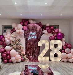 the entrance to a party with balloons and streamers on the wall, surrounded by pink and white decorations