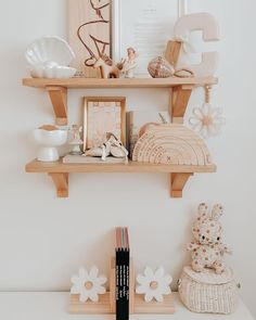 two wooden shelves filled with different items on top of a white table next to a framed photograph