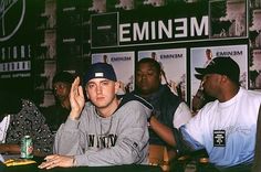 two men sitting at a table in front of a sign with emim on it