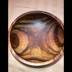 a wooden bowl sitting on top of a table next to a white and brown checkered cloth