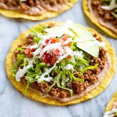 several tacos with meat, lettuce and cheese on them sitting on a table