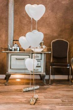 white balloons are floating in the air near a table and chair with wine glasses on it