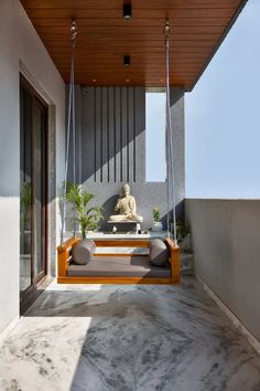 a porch swing with a buddha statue in the background and potted plants on either side