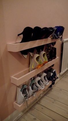 there are many pairs of shoes on the shelf in this room with pink walls and wood flooring