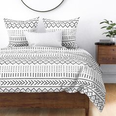 a white and black bed in a bedroom next to a wooden dresser with potted plants