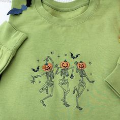 Embroidered Halloween Skeleton Sweatshirt | Dancing Pumpkin Sweatshirt | Fall Spooky Season Pullover | Unisex Party Sweater Embrace the eerie elegance of autumn with our meticulously embroidered Halloween sweatshirt. Featuring a whimsical dancing skeleton and pumpkin design, this cozy pullover captures the essence of the spooky season. Perfect for Halloween parties or chilly fall evenings, this unisex sweater combines comfort with style, making it a must-have for anyone who loves to celebrate th Halloween Embroidered Streetwear Top, Halloween Streetwear Embroidered Top, Fall Skull Print Long Sleeve T-shirt, Long Sleeve Skull Print T-shirt For Fall, Halloween Embroidered Long Sleeve T-shirt, Halloween Long Sleeve Embroidered T-shirt, Embroidered Long Sleeve T-shirt For Halloween, Hand Embroidery Sweatshirt, Halloween Hand Embroidery