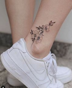 a woman's foot with a flower tattoo on the side of her leg,