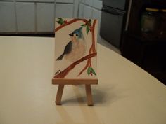 a small easel sitting on top of a table with a bird painted on it