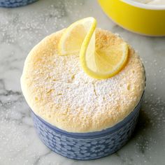 there is a small cake with lemon slices on it and two bowls in the background