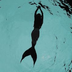 a woman swimming in the water with her shadow on the wall above her head and body