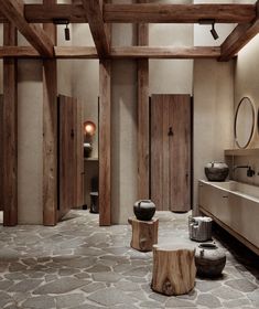 a bathroom with stone flooring and wood accents on the walls, along with two wooden stools