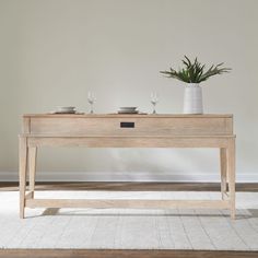 a wooden table with two glasses on it and a potted plant next to it