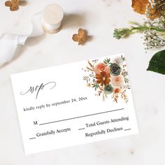 an envelope with flowers on it next to some leaves and other things in the background